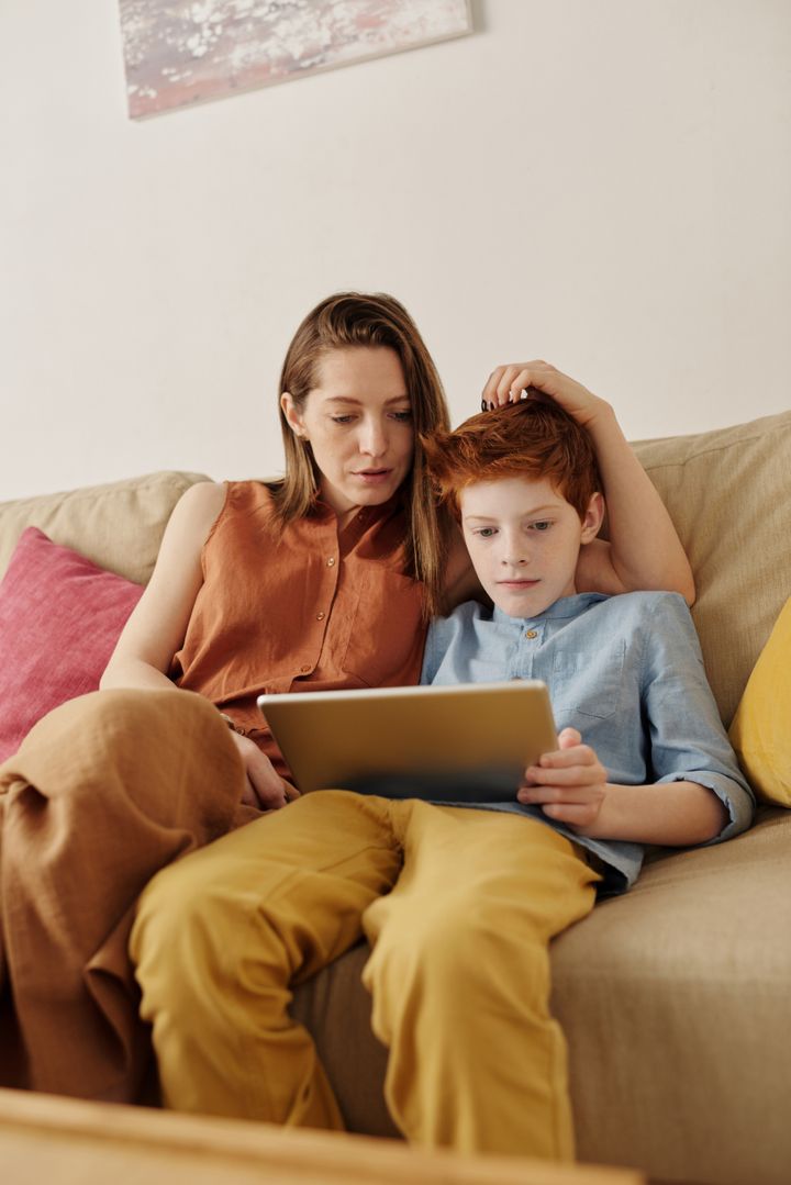 Mãe e filho assistindo no tablet no sofá